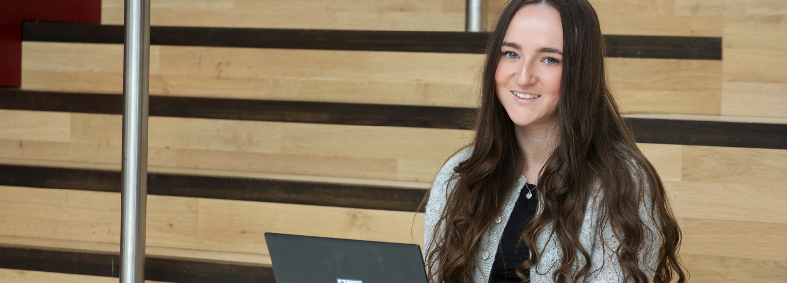 female student on a laptop sitting on staircase